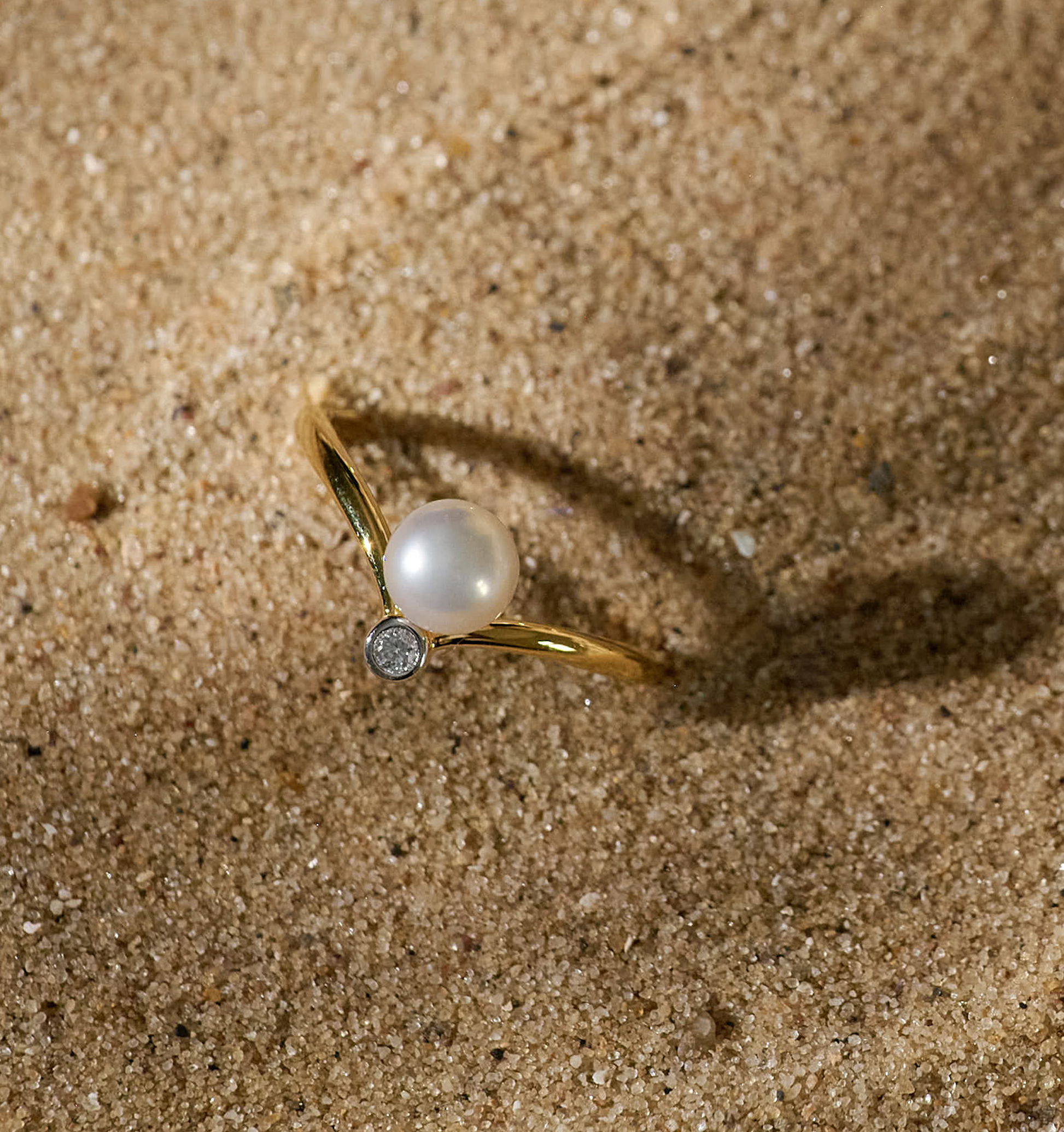 Sirna Ring gold band with pearl and star detail on sandy background