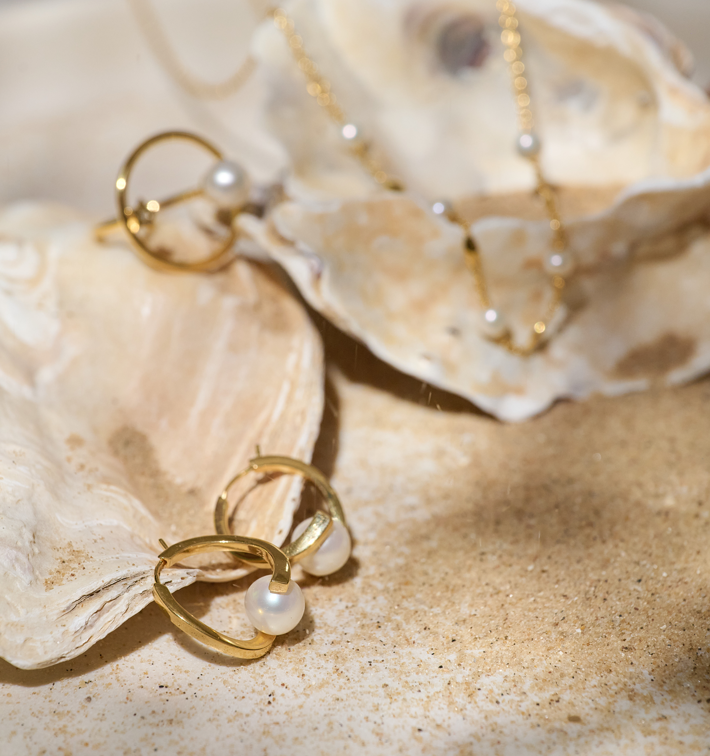 Sharvani Earrings gold hoops with pearls on sandy seashell background