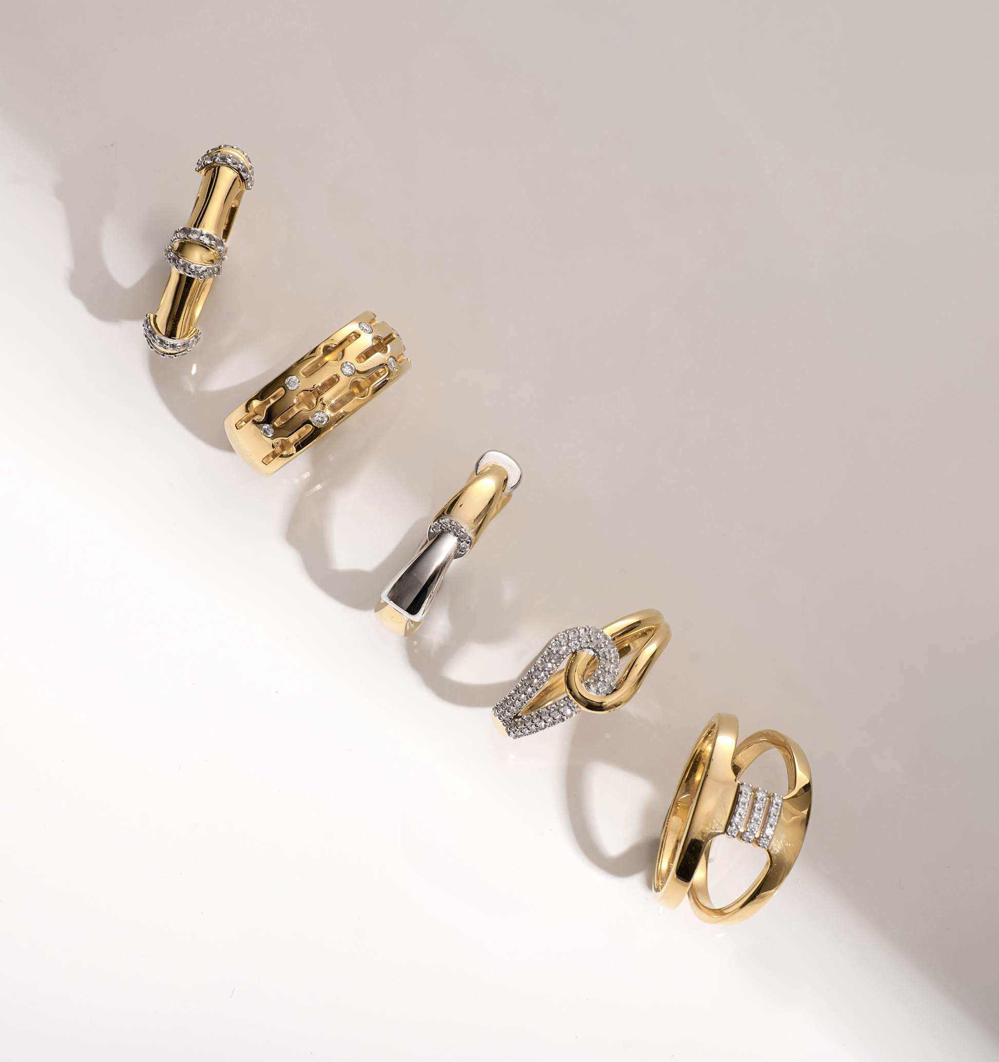 Collection of gold and white topaz rings including the Sahaya Ring with intertwined paths and knot design
