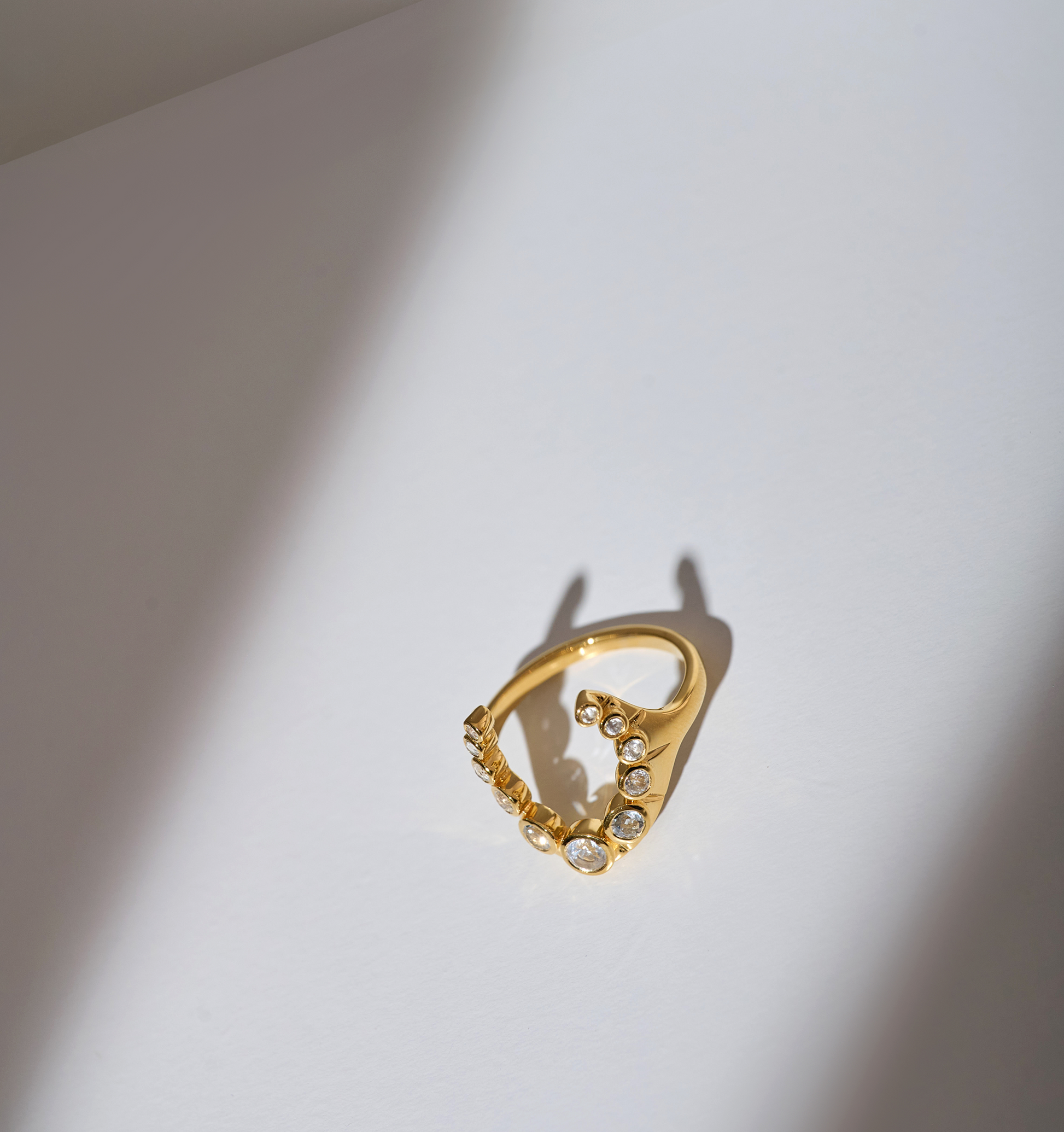 Gold Rakira Ring with 11 white topaz stones in crescent horseshoe design on white background