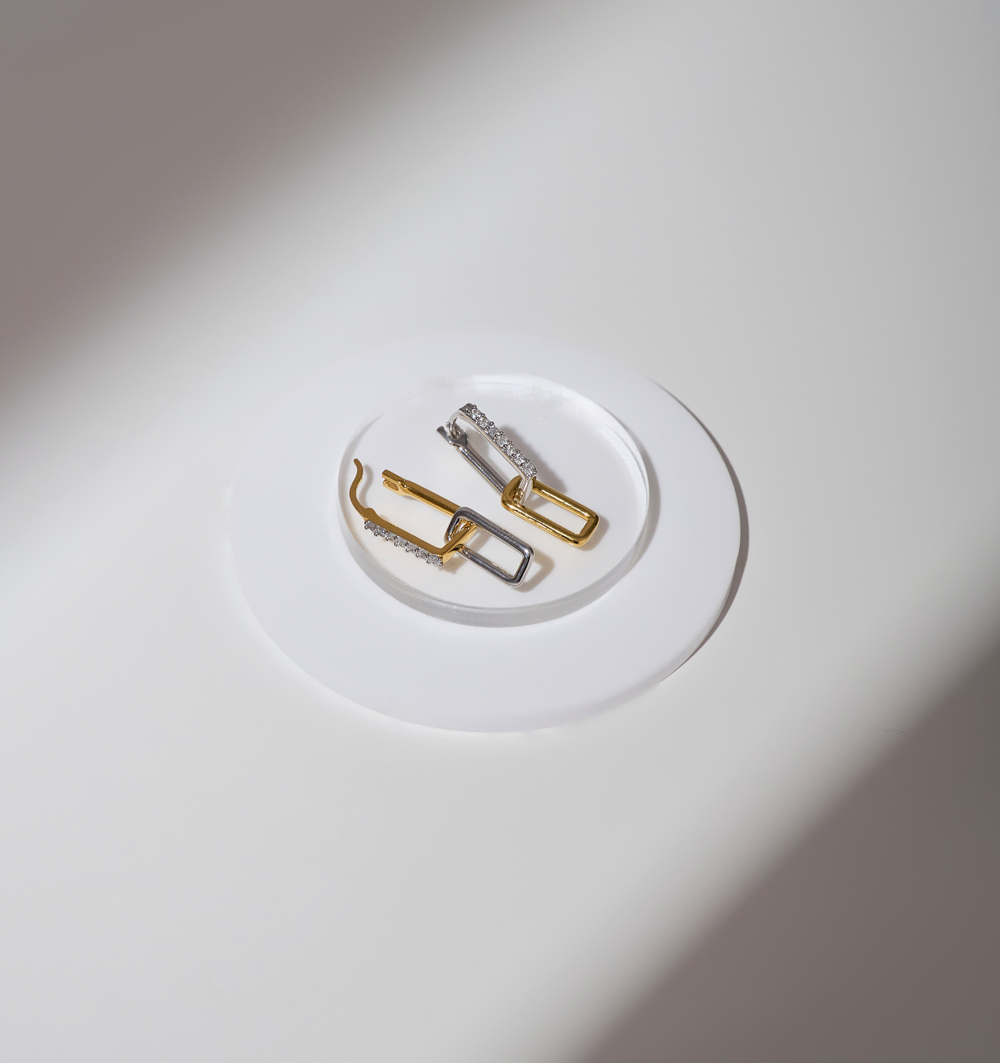 Bandha Earrings in gold and silver on a white plate symbolizing balance and strength