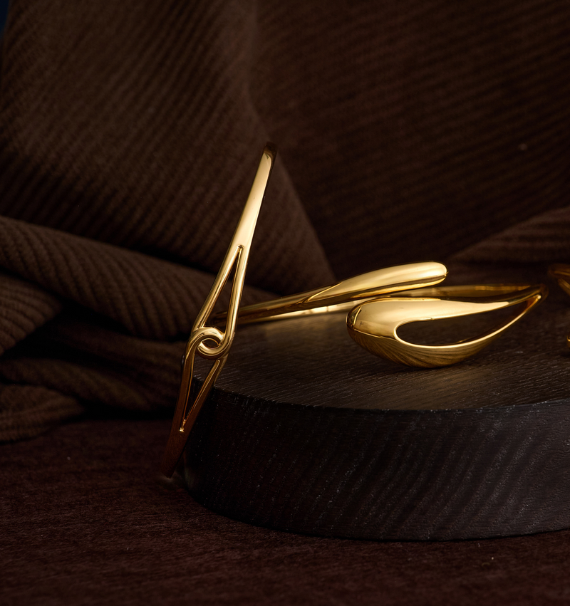 Minimalist gold Vetra Cuff with clean lines and bold design displayed on dark fabric and wood background