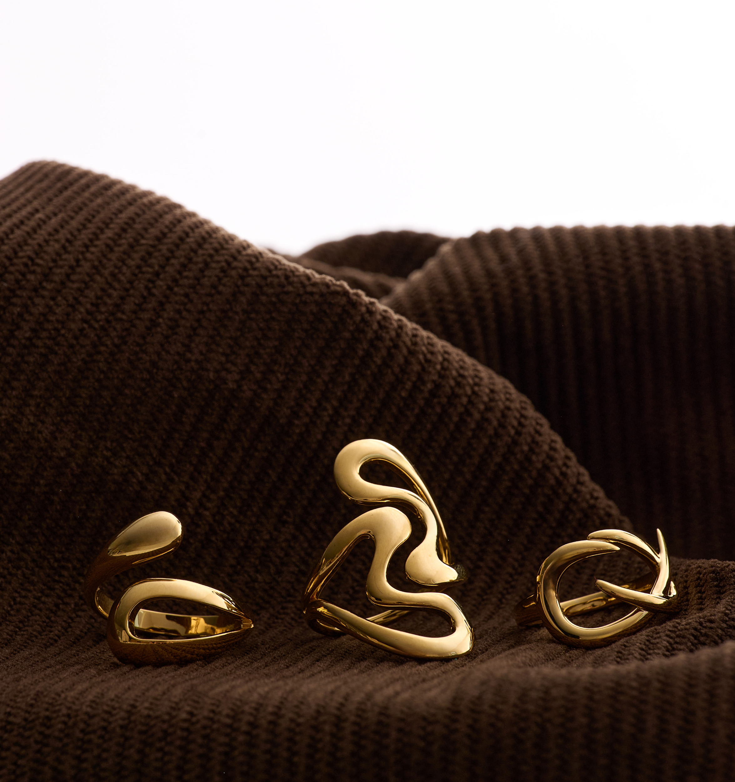 Samvaar Ring radiant gold with two fluid intertwining hearts symbolizing unity on brown fabric