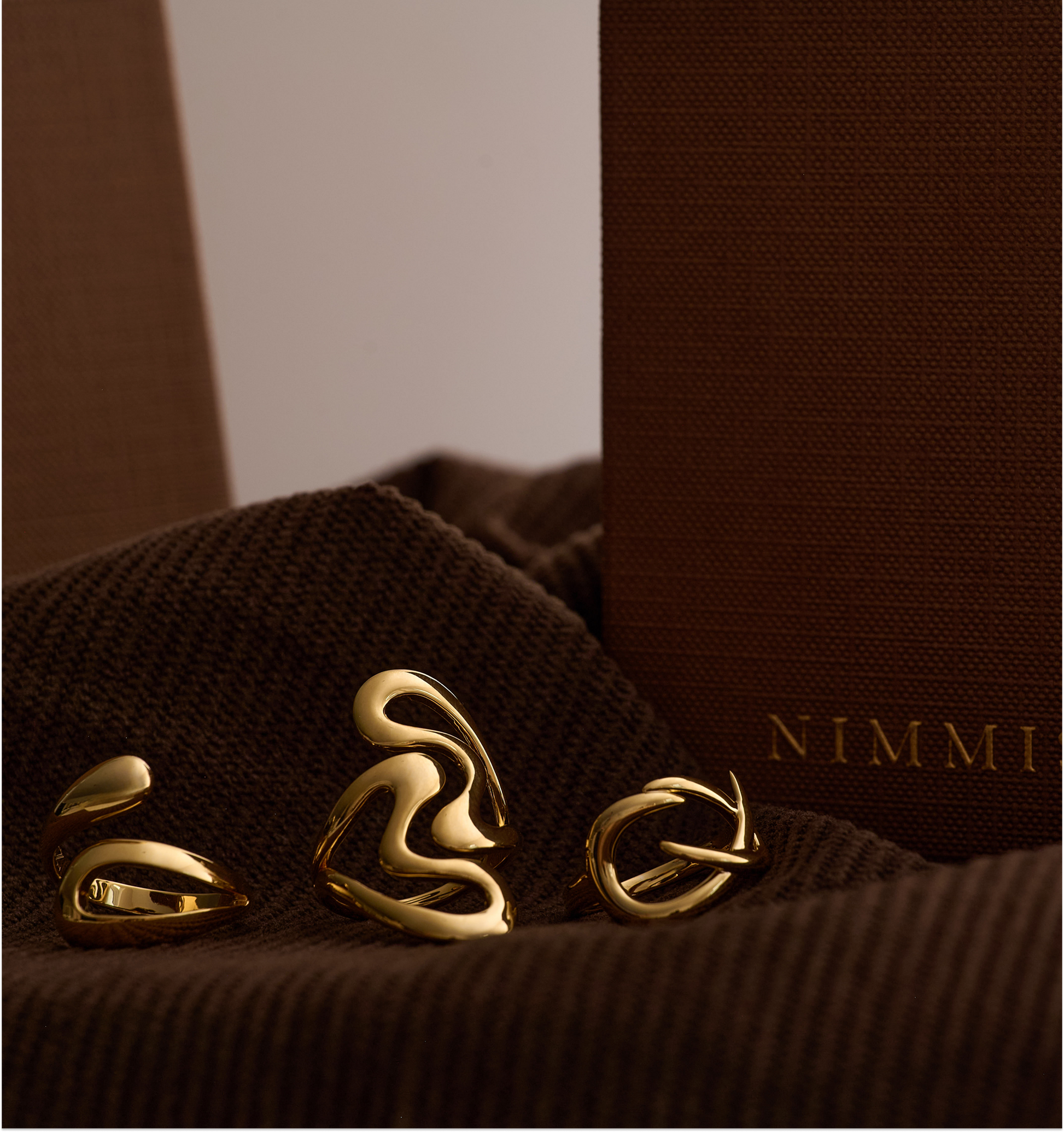 Elegant gold Karvat Ring with fluid, sculpted curves symbolizing tension and grace on a textured brown background