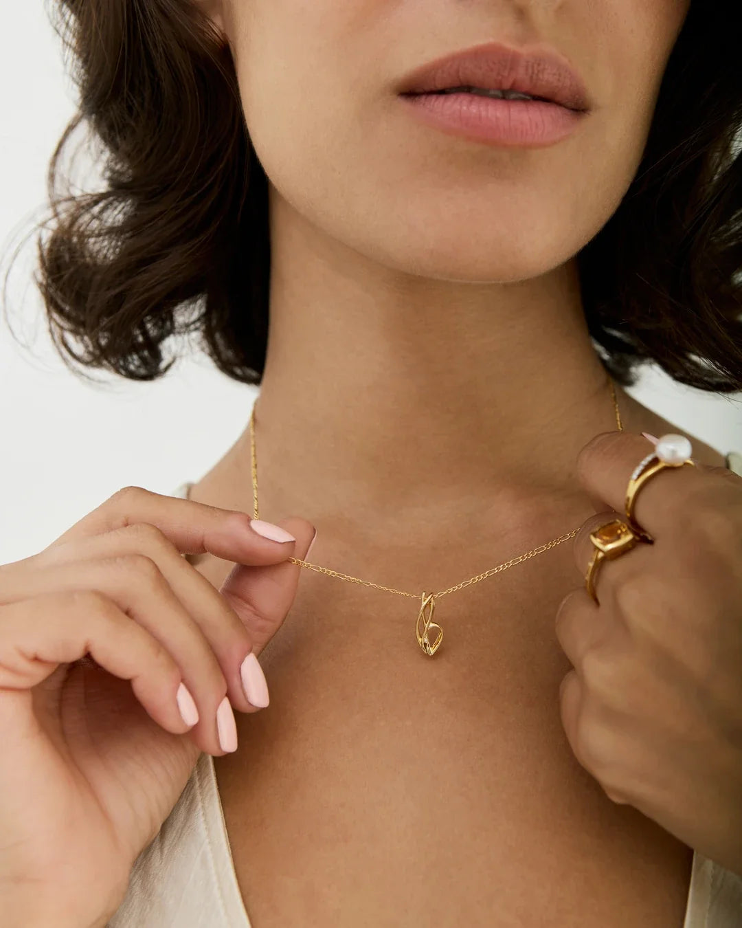 B बी Initial Necklace in polished gold, with a delicate chain and small curved B-shaped pendant on a model’s neck.