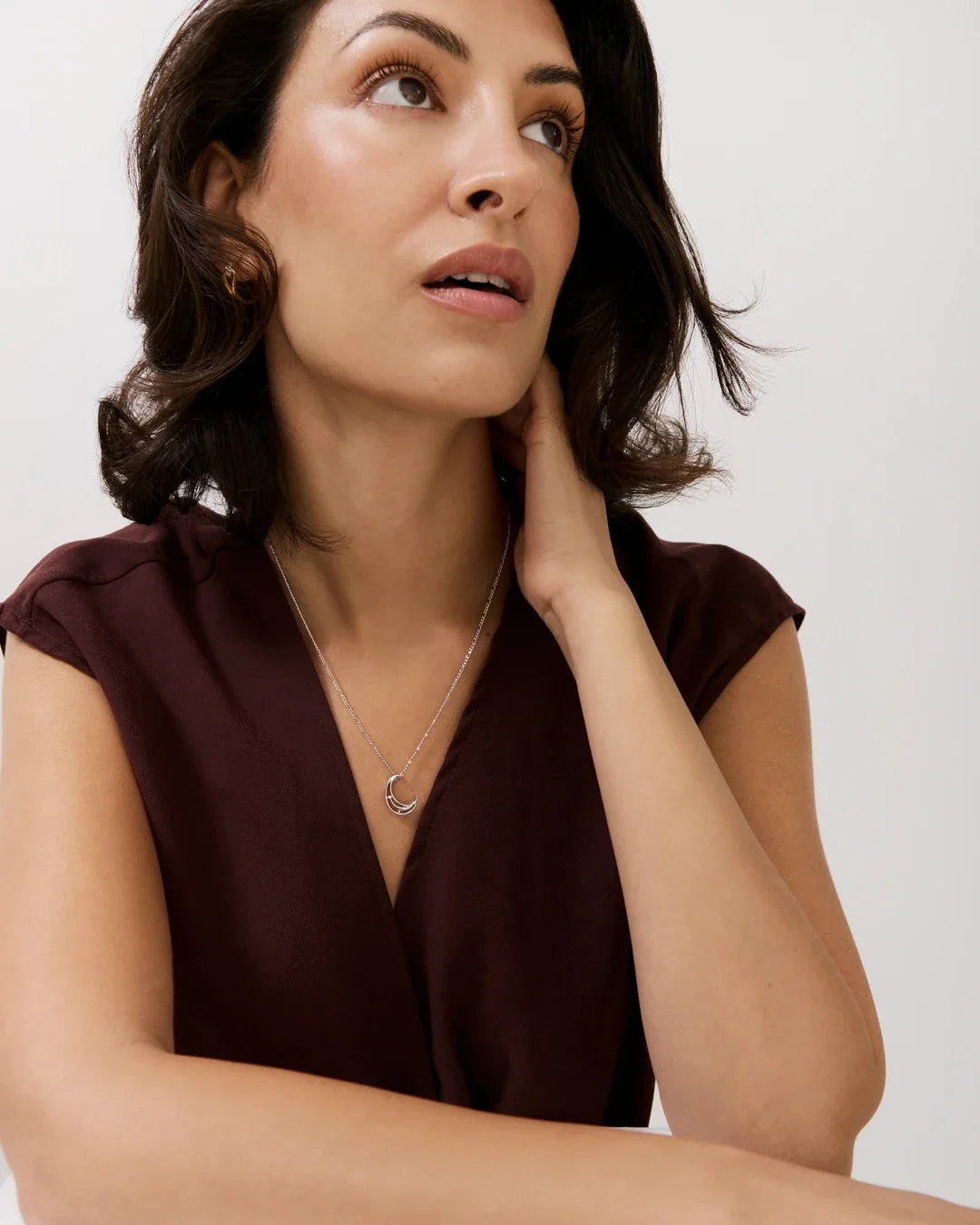 C सी Initial Necklace in a fine silver-tone chain with a small open-circle pendant, worn over a burgundy V-neck top.