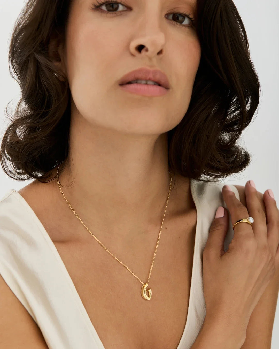 G जी Initial Necklace with a delicate gold-tone chain and small curved G-shaped pendant, worn as a fine everyday necklace