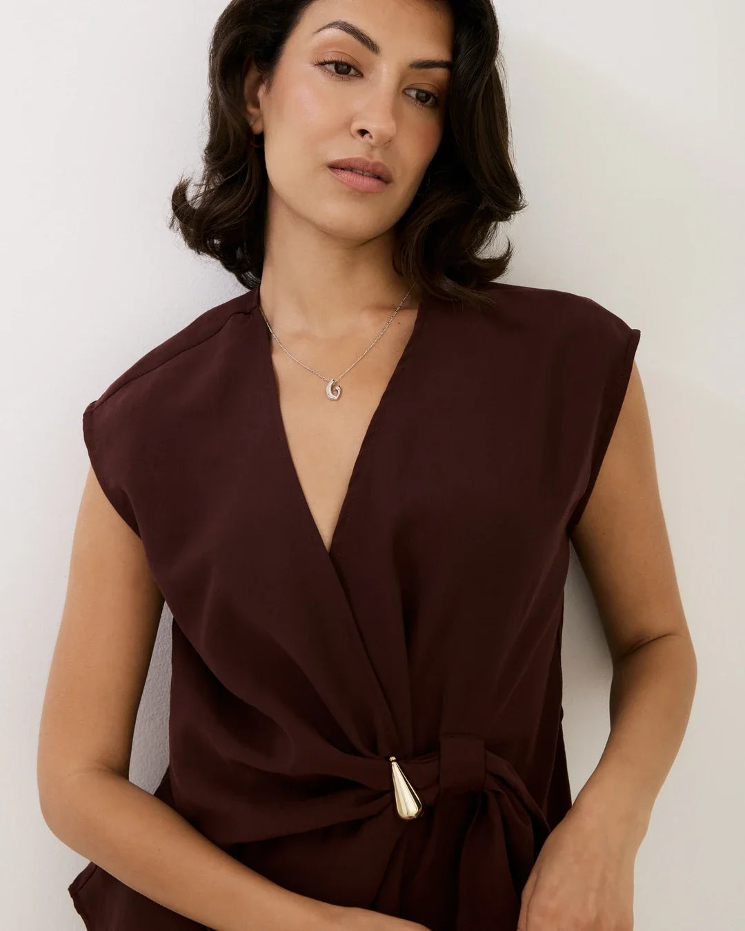 G जी Initial Necklace with a delicate silver-tone pendant and fine chain, worn with a deep burgundy sleeveless top.