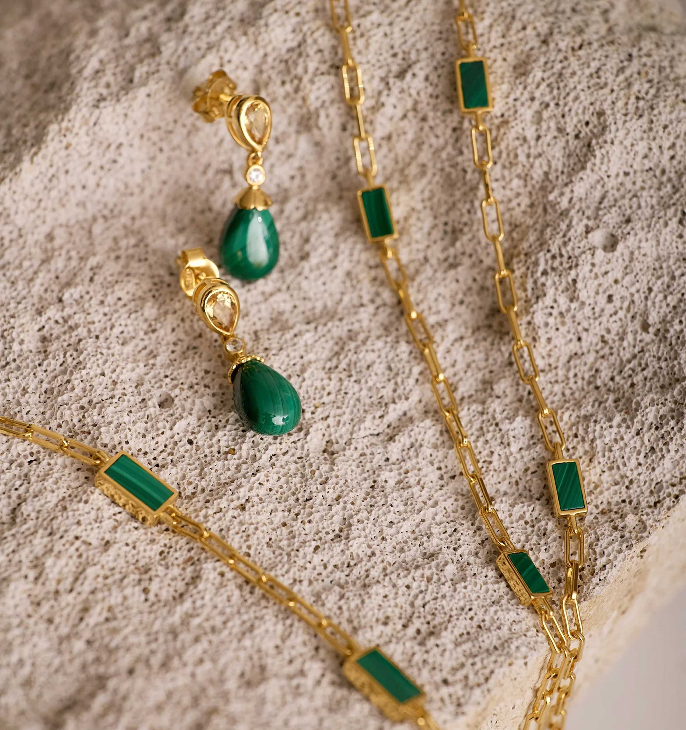 Triya Earrings with green malachite stones and gold accents on textured surface