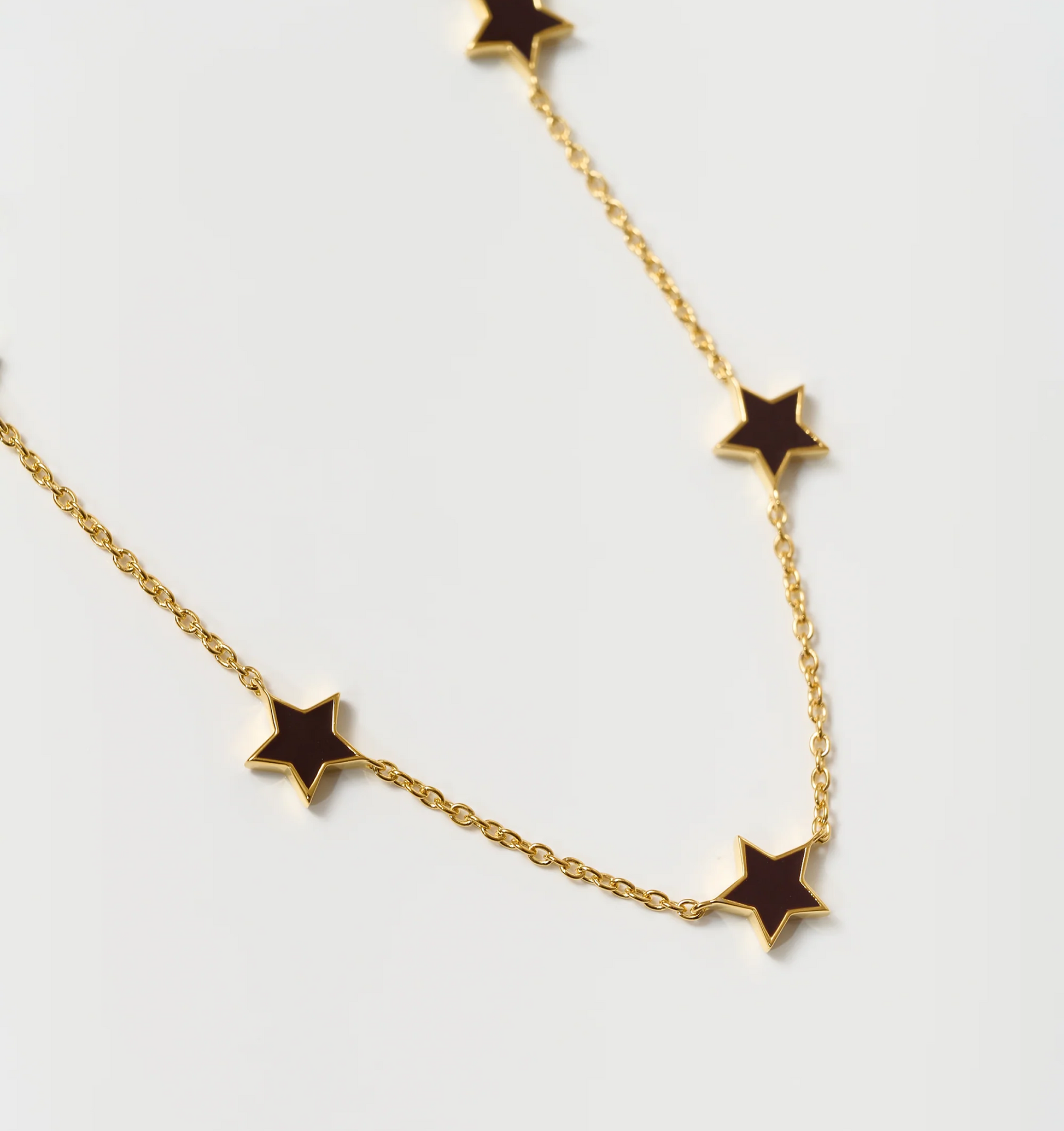 Noctra Necklace gold chain with black star-shaped pendants on white background