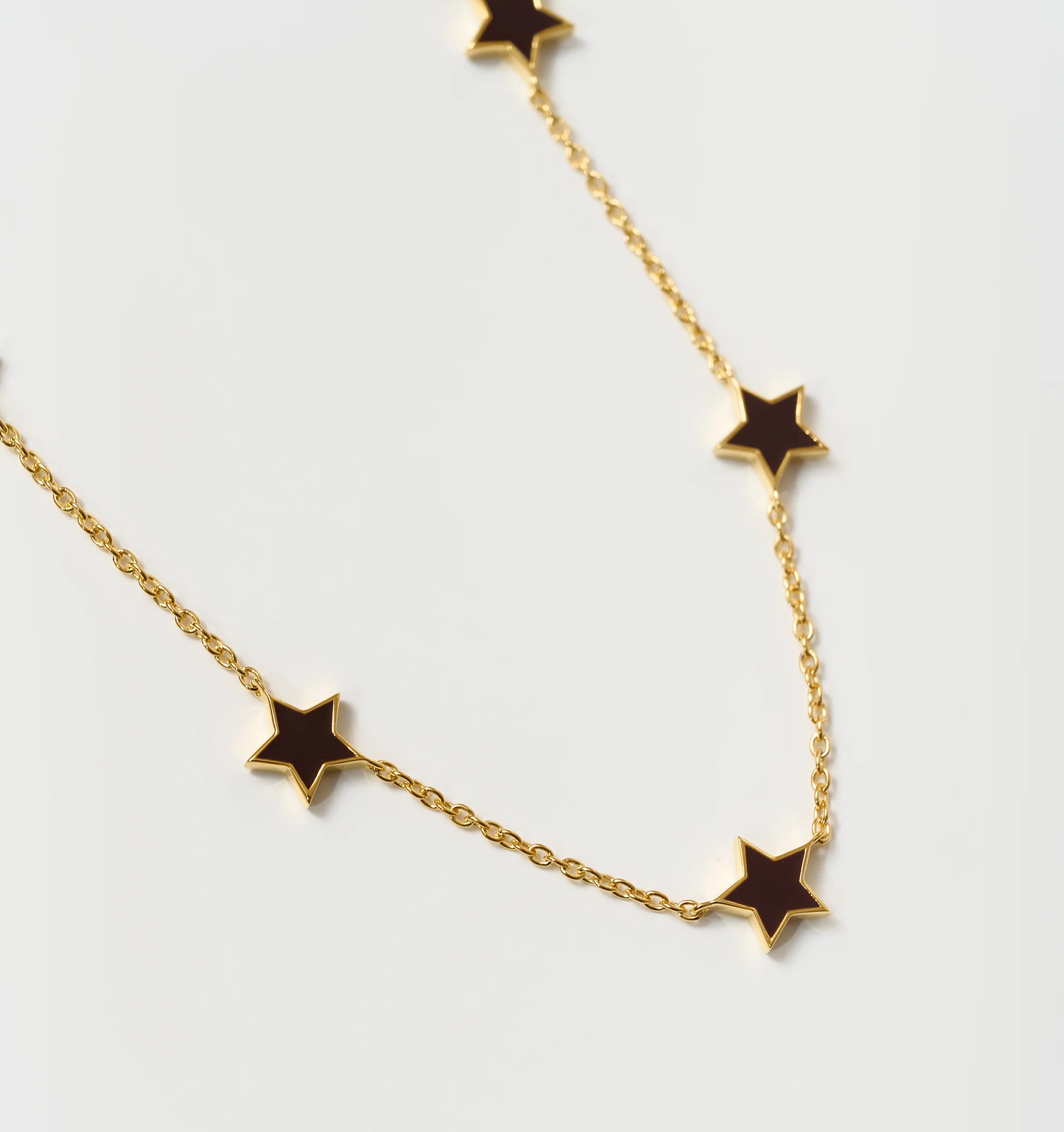 Noctra Necklace gold chain with black star-shaped pendants on white background