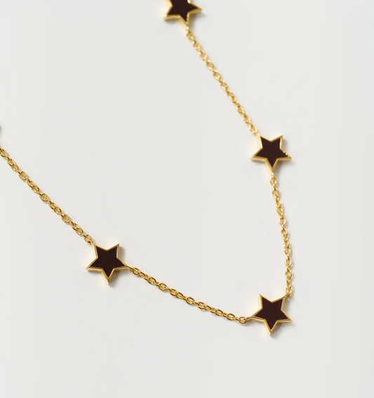 Noctra Necklace gold chain with black star-shaped pendants on white background