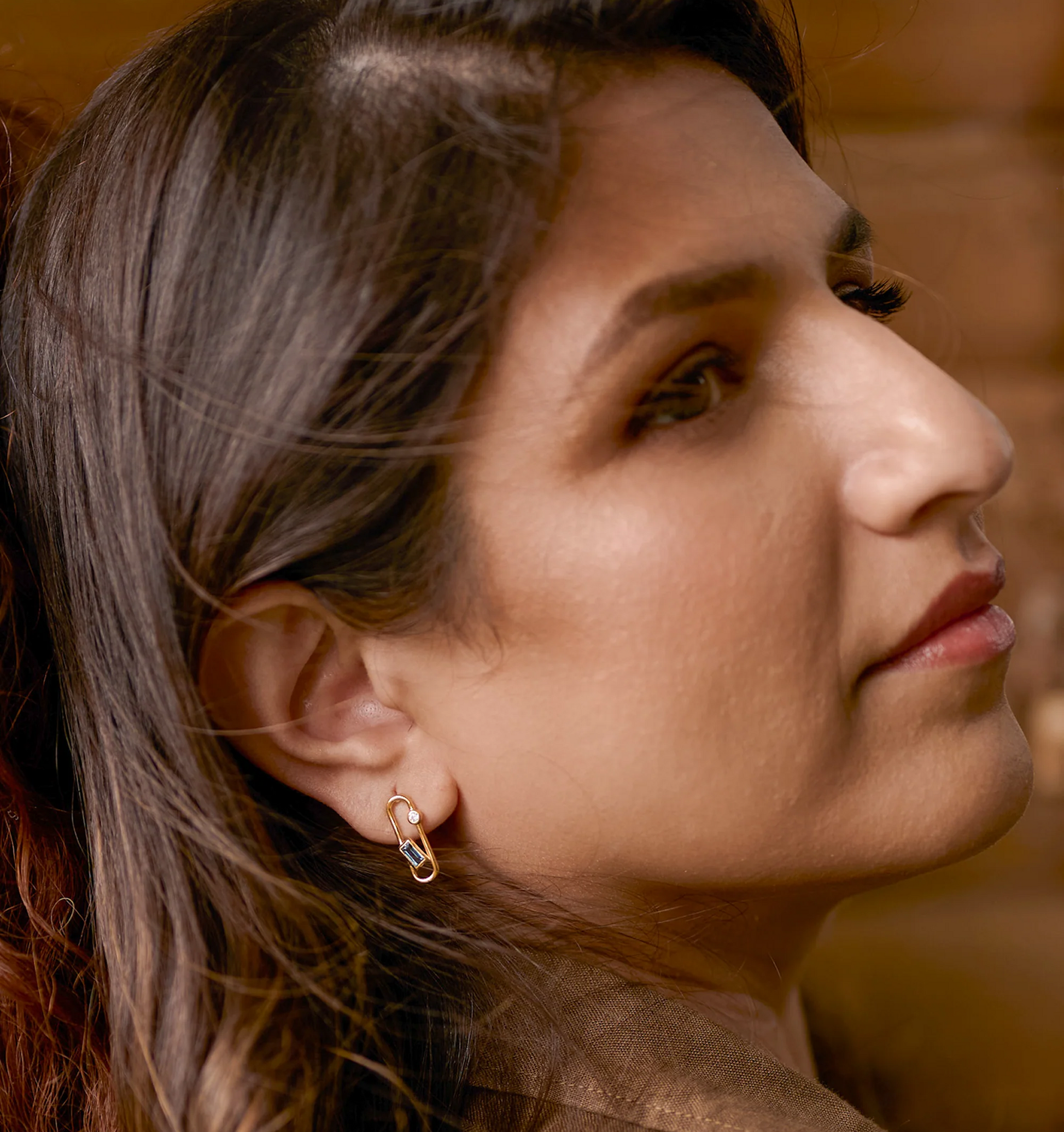 Close-up of a woman wearing elegant Aarka Earrings featuring London Blue Topaz and White Zircon for radiant, silent strength.