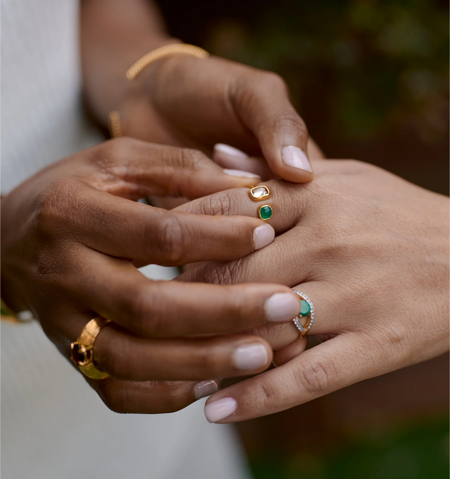 Close-up of hands wearing the Tulaa Ring with green onyx and morganite stones set in gold