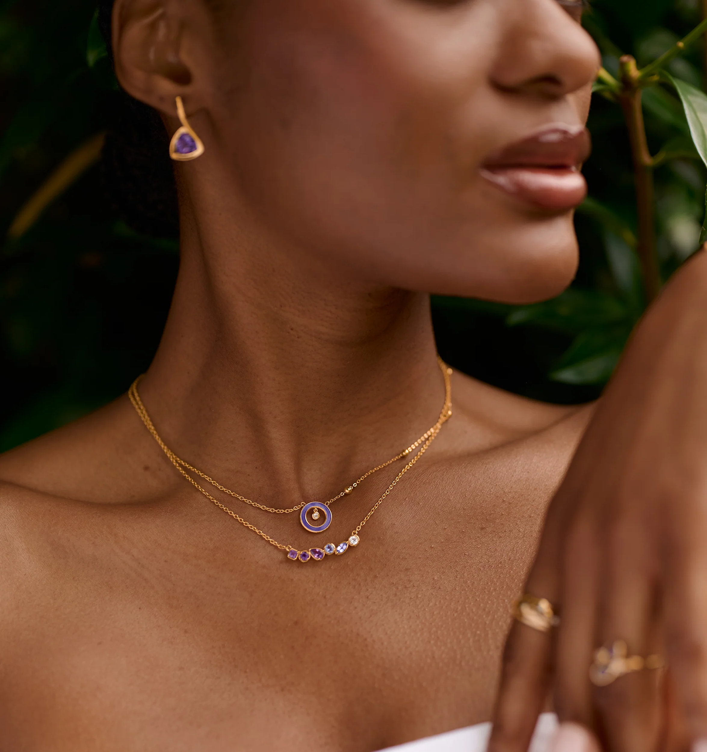 Raag Necklace with layered gold chains featuring amethyst and tanzanite gemstones on a woman