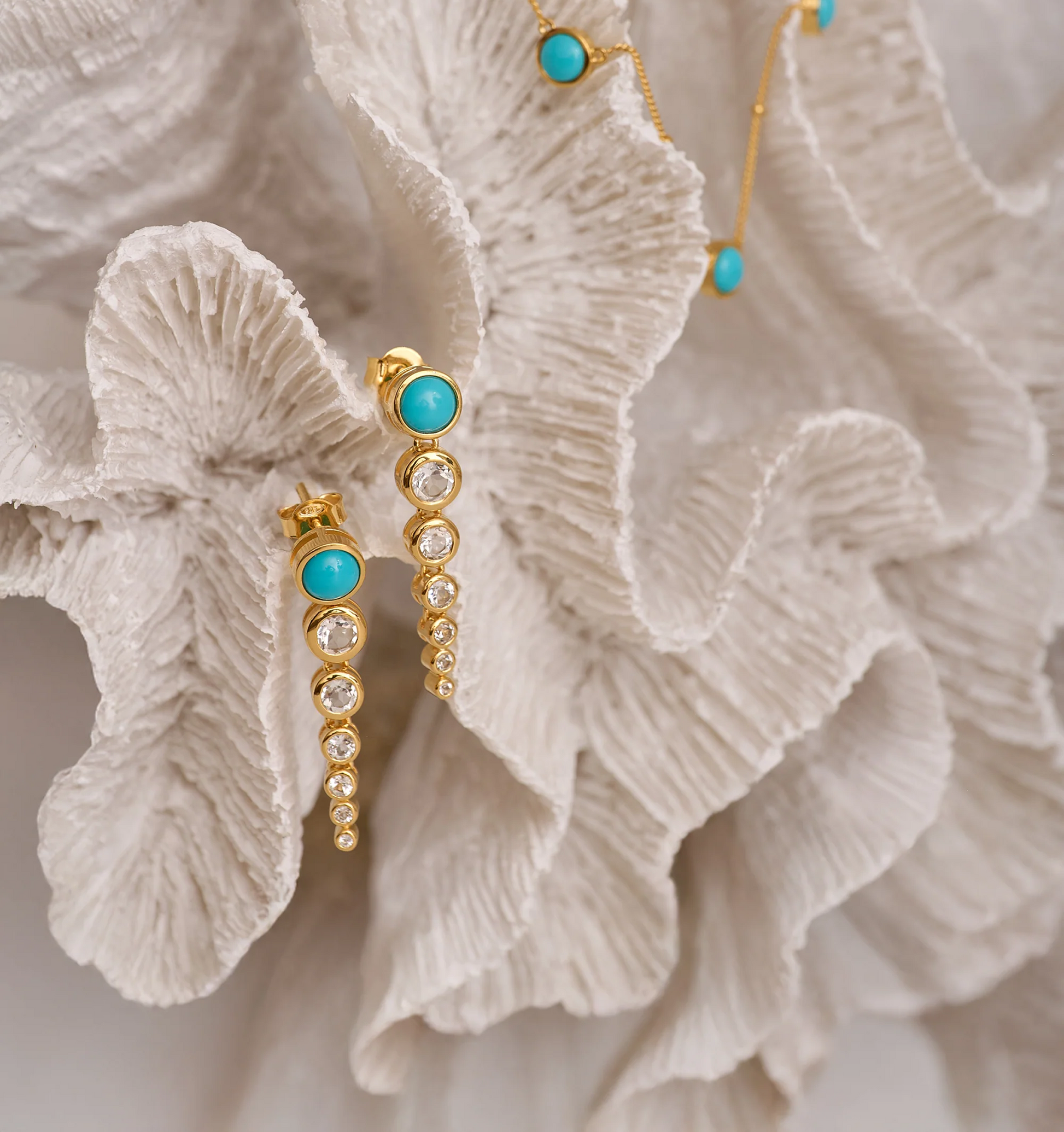 Samaara Earrings with turquoise and white topaz on textured white background