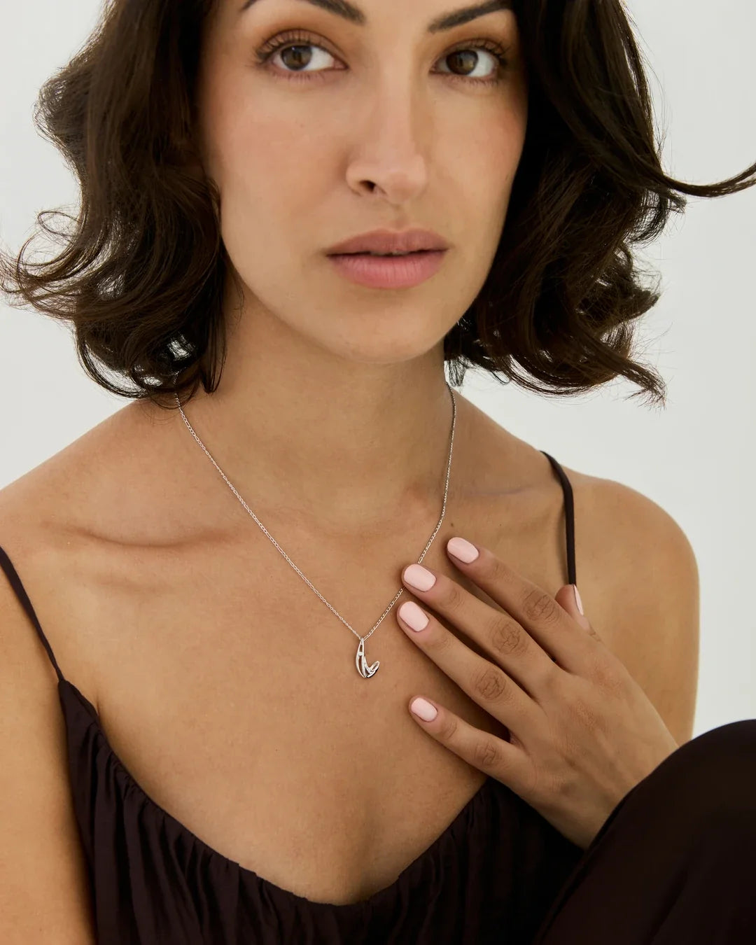 L एल Initial Necklace, a delicate silver-tone chain with a small polished letter L pendant and shadow detail.